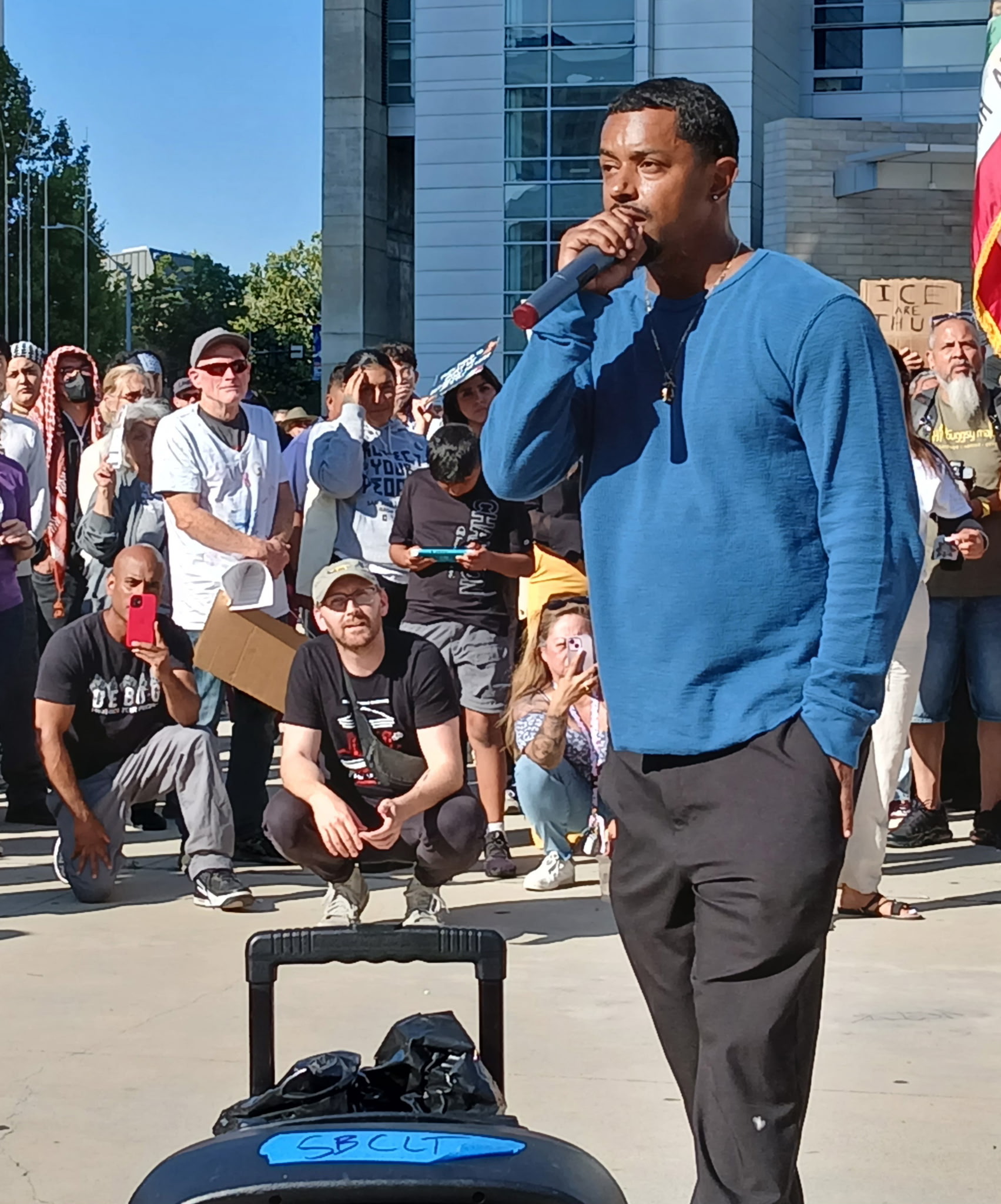 Raymond Goins speaking into a microphone at an outdoor rally